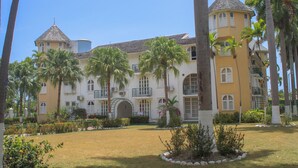 Un grand bâtiment doté d’une tour, entouré de palmiers et d’une pelouse bien entretenue.