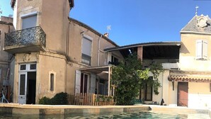 Um edifício com piscina, varanda e uma igreja ao fundo.