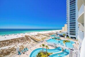 Ein Resort mit Blick auf den Strand, mehreren Schwimmbecken und einem Hochhaus.