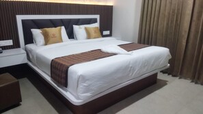 Una habitación de hotel con una cama grande, una mesita de noche y un otoman marrón.