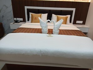 Una habitación de hotel con una cama, dos mesitas de noche, un teléfono y un cojín decorativo.