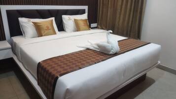Cama bem arrumada com toalha em formato de cisne, manta xadrez e dois travesseiros com logotipos.