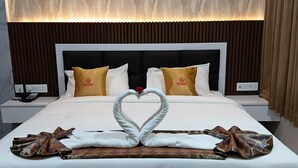 A hotel room with a large bed, a heart-shaped towel decoration, and a patterned wall. - Murugammal Residency (Tirupattur)