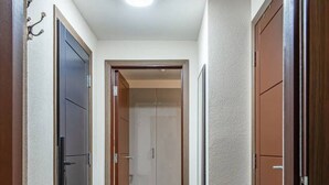 Un pasillo con un aparador de madera, una lámpara en el techo y una puerta que da a un armario.