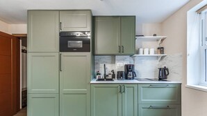 Una cocina compacta con horno integrado, cafetera y hervidor sobre la encimera.