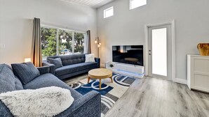 Una sala de estar moderna con sofá, televisión y una pequeña mesa de centro.
