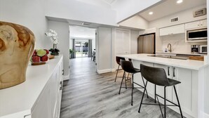 Una cocina moderna con encimera blanca, taburetes negros y una isla grande.
