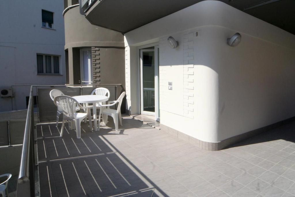 A balcony with a table and chairs, a door, and a window.