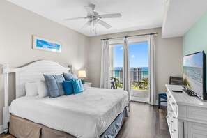 A hotel room with a bed, a desk, a ceiling fan, a TV, and a balcony with a view of the ocean. - ☀️Walk to Beach | Gulf Views | 3 Pools | Ariel Dunes II 1507☀️ (Miramar Beach)