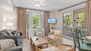 A living room with a sofa, chairs, a coffee table, a TV, and a balcony with outdoor furniture. - 🦀Lagoon Pool | Hot Tub | Walk to Baytowne Wharf | Market Street Inn 232/234🐚 (Miramar Beach)