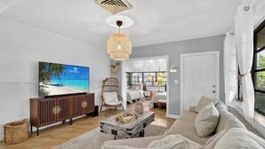 Ein Wohnzimmer mit Fernseher, einer Couch, einem Couchtisch und einem Essbereich mit Stühlen.