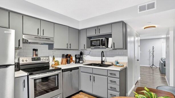 A modern kitchen with grey cabinets, stainless steel appliances, and a wooden dining table. - Newly Remodeled Condo in the Heart of Springfield (Springfield)