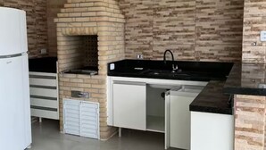 A kitchen with a brick wall, a sink, and a refrigerator.