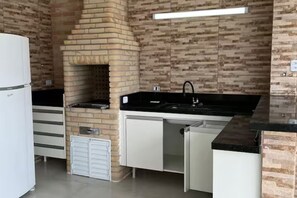 A kitchen with a brick wall, a sink, and a refrigerator. - Cozy house in gated community Morada da Praia Recanto Lira (Bertioga)