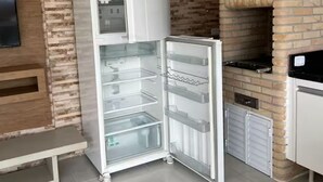 A kitchen with a refrigerator, a brick oven, and a bench.