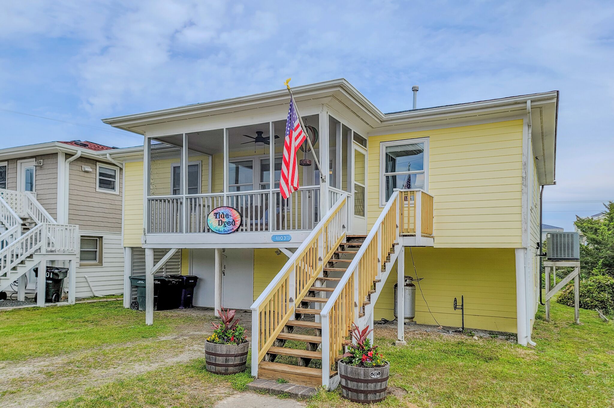 Ein zweistöckiges Haus mit Veranda, Treppe und einer US-amerikanischen Flagge.