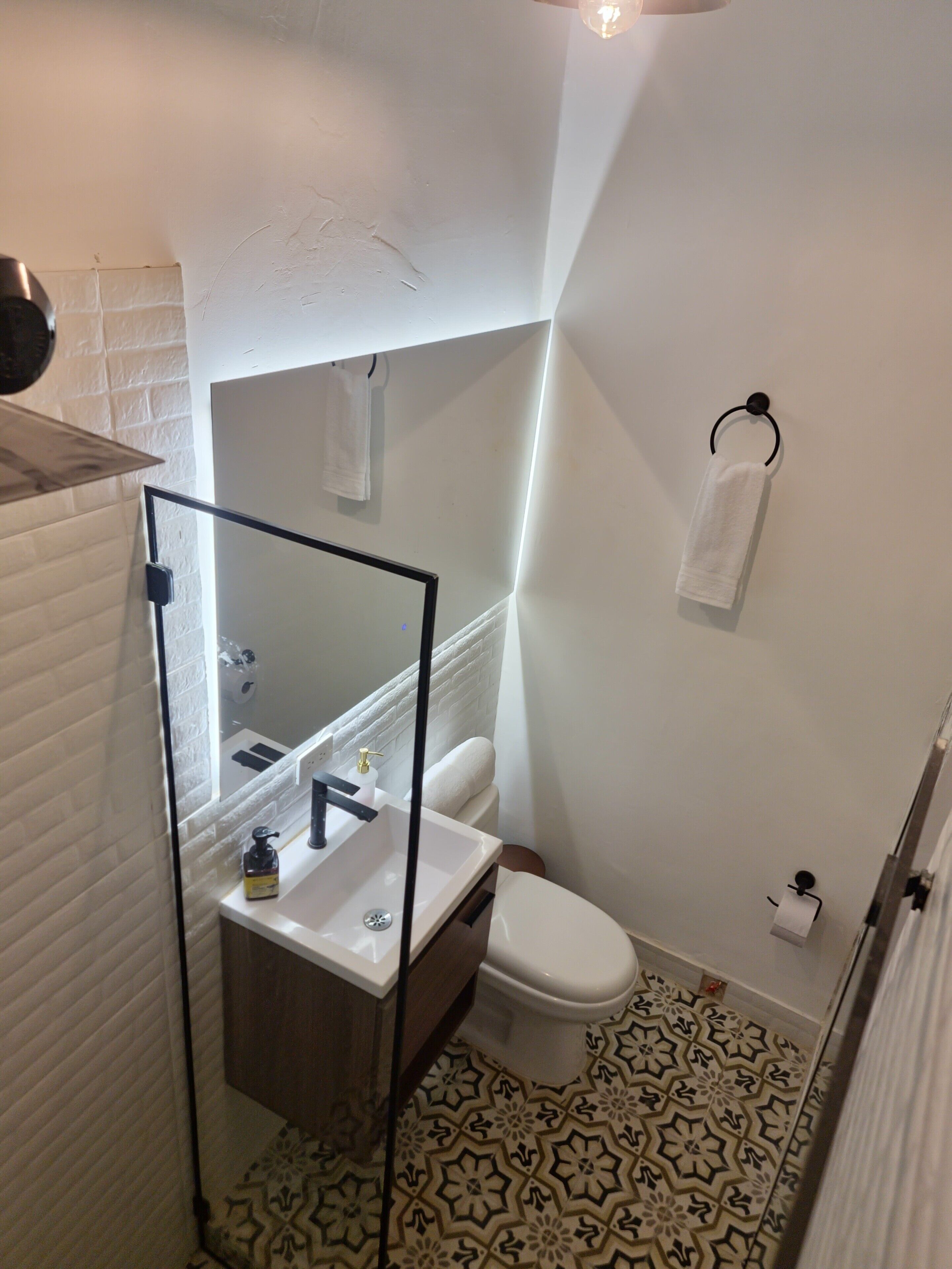 A bathroom with a white sink, toilet, and a mirror with a black frame.