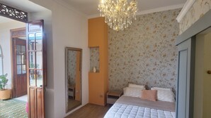 A bedroom with a bed, a chandelier, a mirror, and a door. - Hotel Casa Dharma (Popayán)