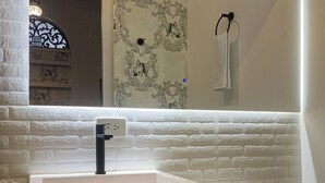 A bathroom with a white sink, wooden vanity, a mirror, and a white toilet. - Hotel Casa Dharma (Popayán)