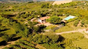 Una propiedad rural con casa, piscina y abundante vegetación alrededor.