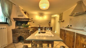 Una cocina con chimenea de ladrillo, mesa de madera y armarios.