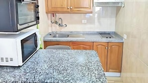 Une cuisine avec des armoires en bois, un plan de travail en granit, un four à micro-ondes et un four encastré.