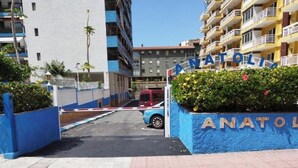 Une entrée fermée par un portail menant à un immeuble résidentiel, avec une plaque indiquant « ANATOLIE ».