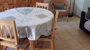 A dining area with a round table, chairs, a television, and a refrigerator.