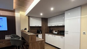 A modern kitchen with white cabinets, a wooden countertop, and a bar area with stools.