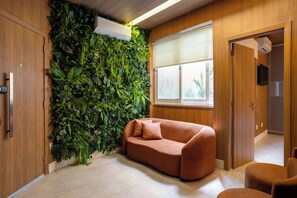 Une pièce avec un mur vert, un canapé marron et une porte en bois.
