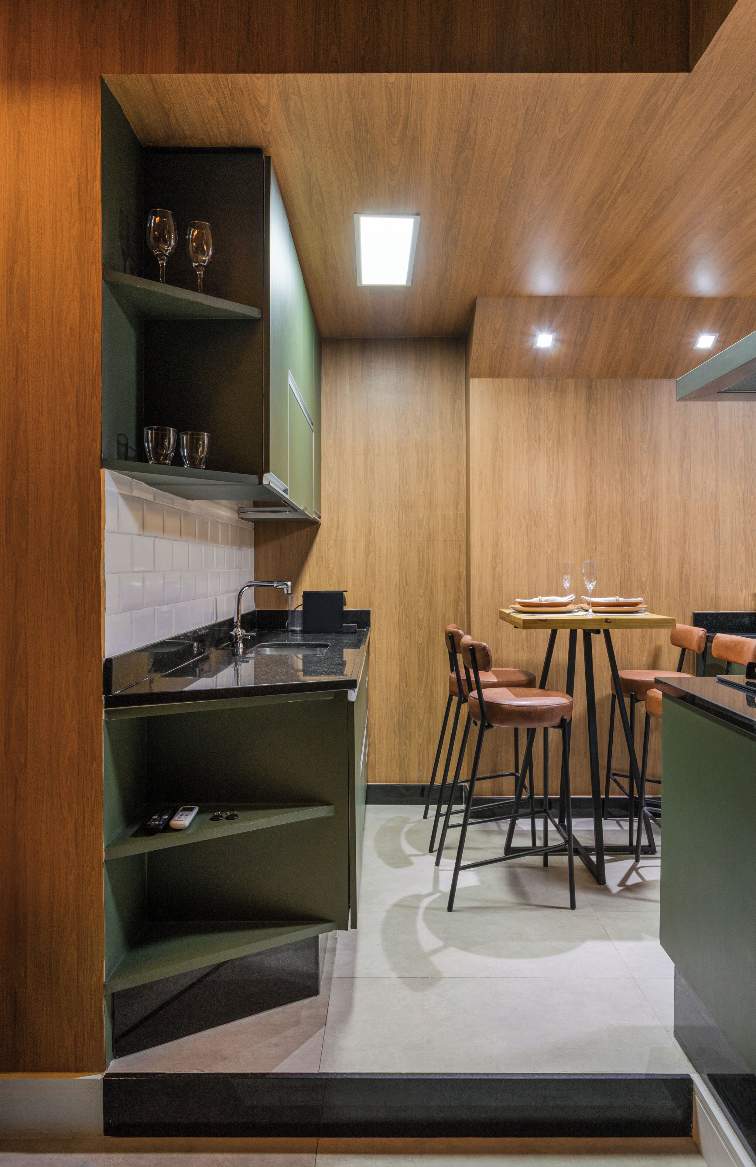 A modern kitchen with a built-in island, wooden cabinetry, and a dining area with chairs.