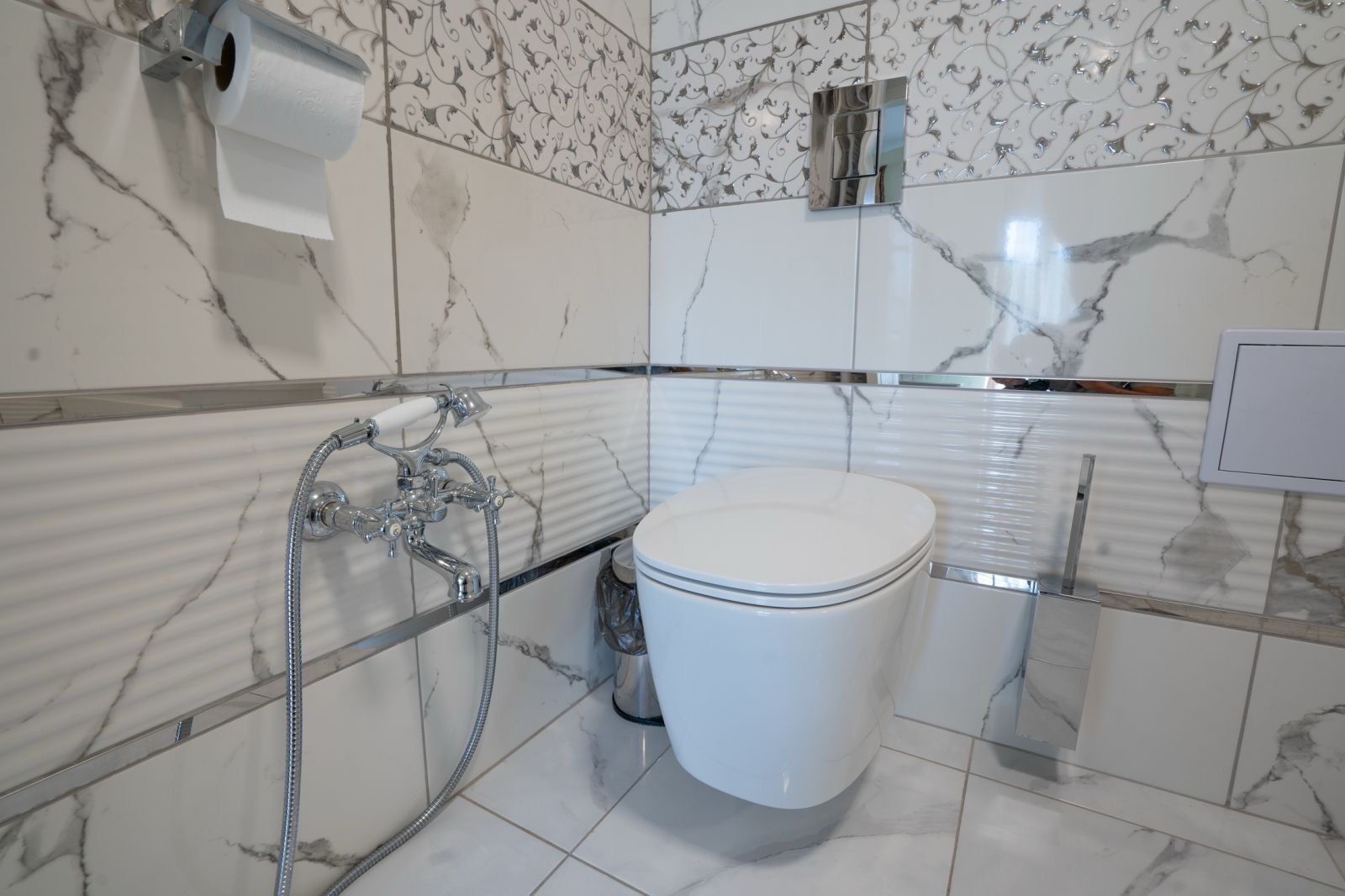 A bathroom with a toilet, a shower, and a toilet paper holder.