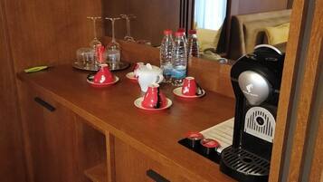 Una kitchenette compacta con cafetera, botellas de agua y un portavasos para copas de vino.