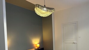 Ein Schlafzimmer mit einem Bett, einem Nachttisch, einer Lampe, einer Tür und einem gemusterten Teppich.