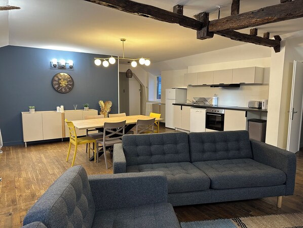 A modern living room with a gray sofa, a dining area with a yellow chair, and a kitchen with white cabinets and a black oven. - Private Apartment - T3+T4 - 190m² - 10 pers - Courtyard&Parking - Hypercentre Bourges (Bourges)