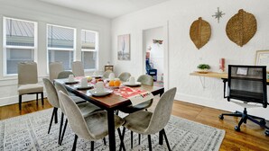 A dining area with a table set for six, a computer desk, and a large window with blinds. - Spacious 6-bedroom apartment in gorgeous Birmingham with AC, secured parking lot (Birmingham)