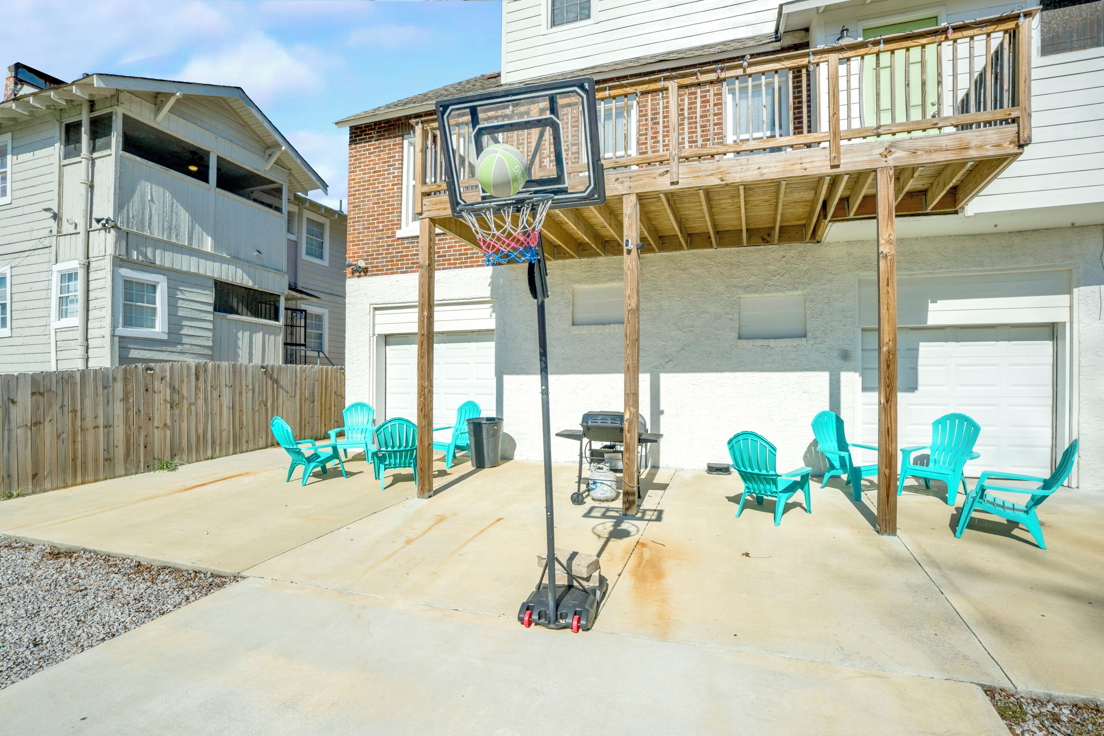 Ein Garten mit einem Basketballkorb, Gartenmöbeln und einer Holzterrasse.