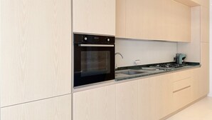 A modern kitchen with light wood cabinetry, a built-in oven, a gas stove, and a stainless steel sink. - P085 – Porto Recanati, new two-room apartment 30 meters from the sea (Porto Recanati)