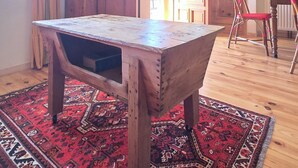 Une pièce avec une table en bois, un tapis rouge à motifs, un meuble et une chaise.