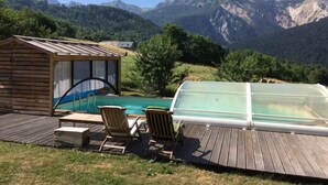 Une terrasse en bois avec une piscine, des chaises longues et un petit abri de jardin.