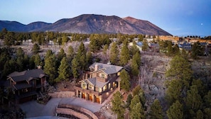 A large house with a stone foundation, multiple decks, and a mountain backdrop. - On trails, 2 mi to town & NAU, 12 mi to Snowbowl (Flagstaff)