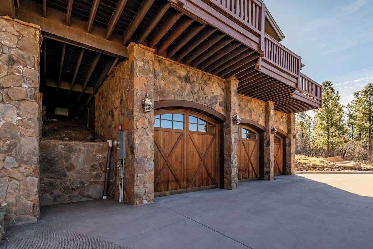 Un edificio de piedra con puertas de garaje de madera y un balcón.