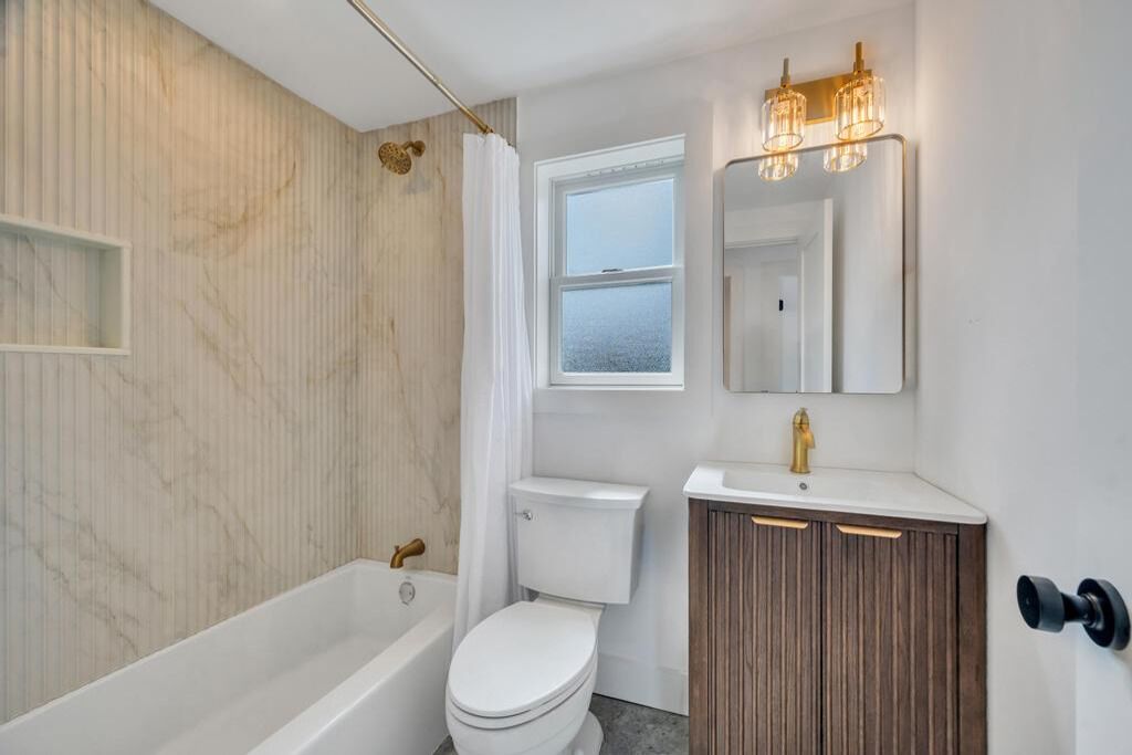 Un baño con bañera, inodoro, tocador y ventana.