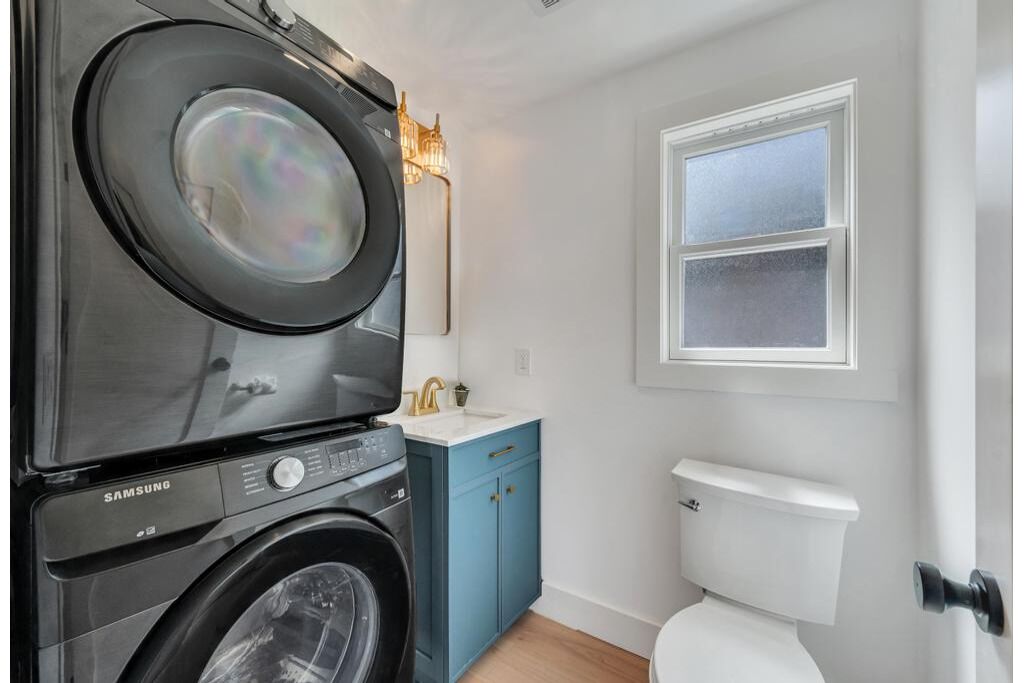 A compact laundry room with a Samsung washer and dryer, a small sink, and a toilet.