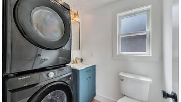 A compact laundry room with a Samsung washer and dryer, a small sink, and a toilet.