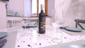 A dining table with a wine bottle, two glasses, and plates. - Orio welcome BGY (Bergamo)