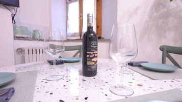 A dining table with a wine bottle, two glasses, and plates, in a room with a window and a radiator.