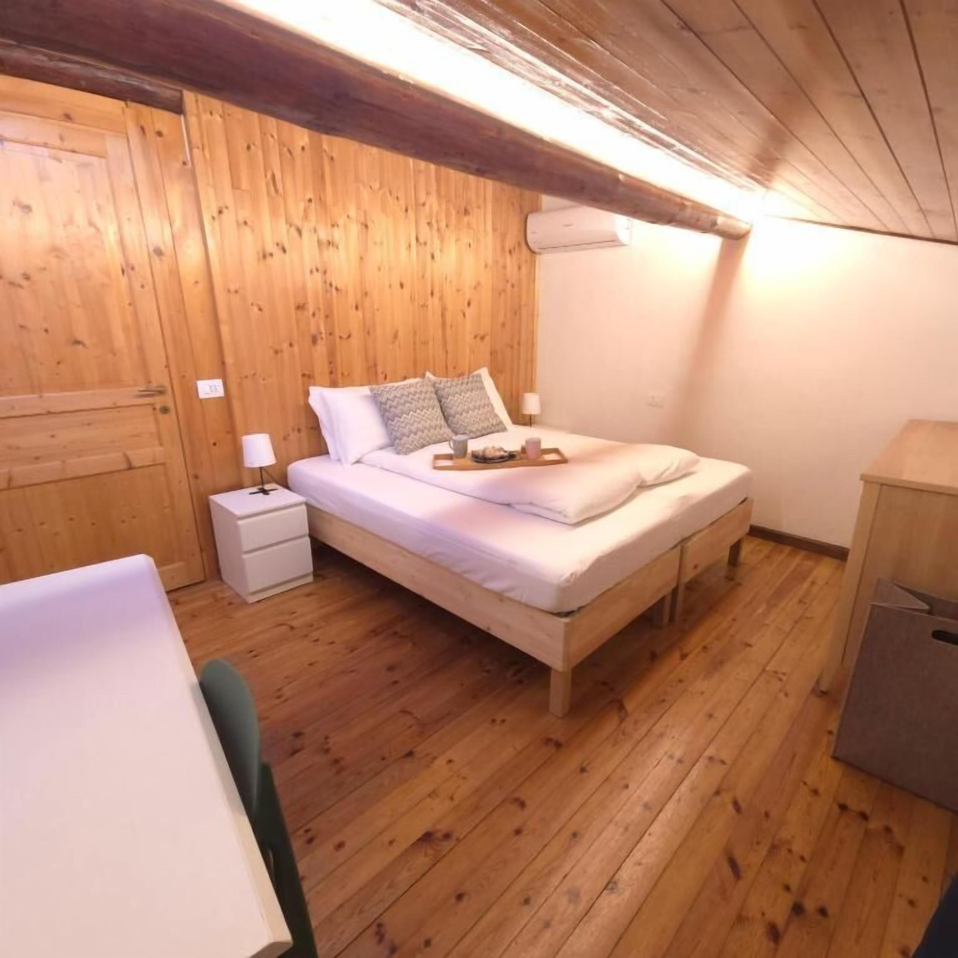 Una habitación con paneles de madera, una cama, una mesita de noche, un escritorio y un armario.