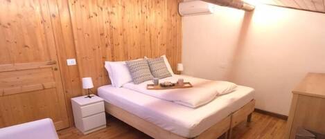 Una habitación con paneles de madera, una cama, una mesita de noche, un escritorio y un armario.