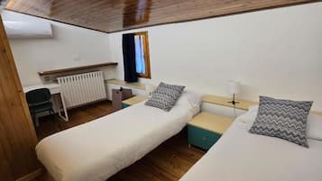 A room with two beds, a desk, a chair, and a window.